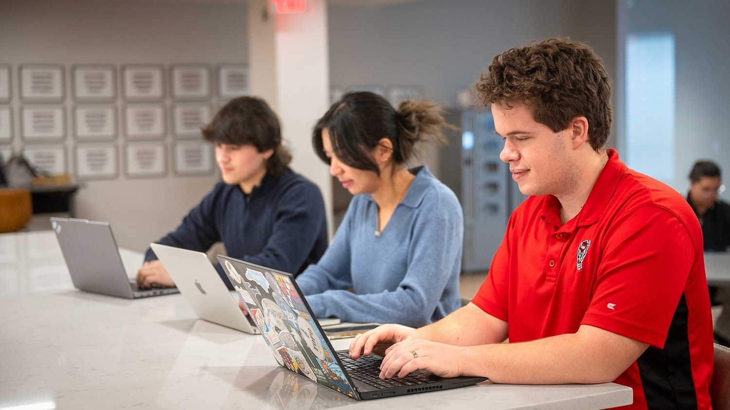 Three students working on laptops.