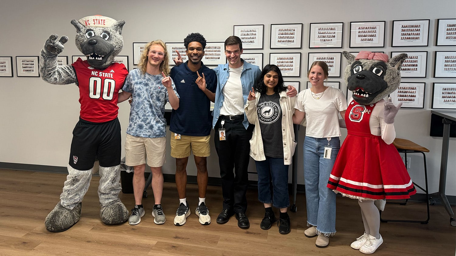 Five graduate students pose with NC State's mascots, Mr. and Ms. Wuf