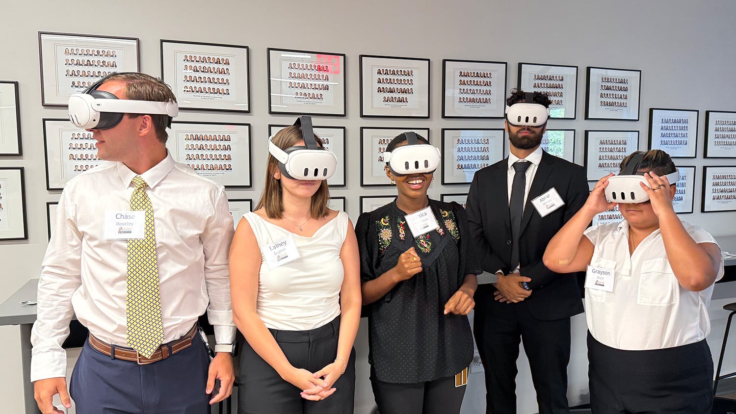 five professionally-dressed graduate students model virtual reality headsets